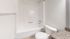 Modern bathroom with sleek white bathtub, elegant granite countertop, and polished fixtures.