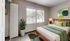 Bright and inviting bedroom with a modern green theme, featuring a comfortable bed, large window with natural light, and stylish decor.