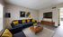Contemporary living room with a sleek navy sofa accented by vibrant yellow pillows, featuring a stylish coffee table and a modern entertainment space.