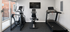 Modern fitness room featuring an elliptical, recumbent bike, and treadmill, complemented by a large window for natural light.