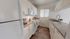Modern kitchen with sleek white cabinetry, granite countertops, and stainless steel appliances, offering a stylish and functional space.