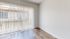 Bright room with sleek wooden flooring and large vertical blinds allowing natural light.