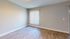 Bright and inviting empty room boasting stylish wood flooring, freshly painted walls, and a large window with vertical blinds allowing natural light to flood in.