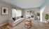 Chic living room with bright natural light, featuring a cozy white sofa, modern decor, and vibrant green plants for a serene ambiance.