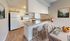 Bright, modern kitchen with sleek white cabinets, a breakfast bar with stylish stools, and a cozy dining area adorned with artistic wall decor.