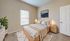 Cozy bedroom featuring a plush bed with elegant bedding, soft carpeting, natural light, and tasteful decor.