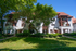 Front exterior of Old Heidelberg Apartments featuring historic architecture, mature shade trees, and landscaped grounds.