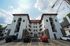 Rear view of Old Heidelberg Apartments showing white stucco construction, stone detailing, exterior stair towers, and resident parking.