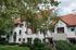 Landscaped courtyard at Old Heidelberg Apartments featuring historic architecture, covered balconies, striped awnings, and mature trees.