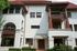 Main entrance at Old Heidelberg Apartments with decorative wood accents, covered balconies, and landscaped garden beds.