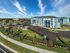 Vibrant blue apartment complex with spacious parking lot, surrounded by lush green lawns and a charming playground under a bright blue sky.