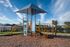 Vibrant playground with modern climbing structures and a shade canopy, set against a picturesque suburban backdrop.