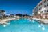 Luxurious apartment complex featuring a sparkling swimming pool and stylish poolside lounge area against a stunning twilight sky.
