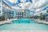 Luxurious apartment complex exterior showcasing a stunning pool, chic cabanas, and palm trees under a vibrant sky.