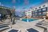Luxurious apartment complex with a sparkling swimming pool, surrounded by elegant lounge chairs and modern cabanas, set against a stunning twilight sky.
