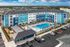 Modern apartment complex with vibrant blue exterior, central swimming pool, and landscaped surroundings, offering resort-style living.
