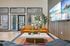 Contemporary living room with a sleek design featuring a stylish orange sofa, a modern marble coffee table, and large windows offering a poolside view.