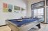 Chic recreational space with a modern pool table, abstract art, and natural light from large windows.