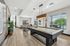 Modern game room with a sleek pool table, elegant lighting, and a cozy seating area by large windows.