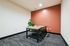 Inviting workspace with a sleek wooden table, modern chairs, and a vibrant orange accent wall, perfect for collaboration.