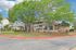 Charming brick apartment complex surrounded by lush green trees and manicured landscaping, offering a serene and inviting atmosphere.