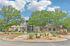 Inviting apartment complex entrance with lush landscaping and a modern brick facade under a bright blue sky.