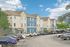 Charming, modern apartment complex featuring colorful facades, ample parking, and lush greenery under a clear blue sky.