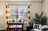 Charming dining nook with a wooden table set by a sunlit window, vibrant striped curtains, and cozy seating in a stylish apartment.