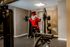 Unique apartment gym with a colorful mascot adding a touch of fun and motivation while lifting weights on top-tier equipment.