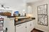 Charming kitchen with modern black countertops, elegant white cabinetry, and artistic wall decor, seamlessly blending into a bright and inviting living space.