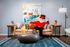 Vibrant living room with modern design, featuring a unique character in a red suit lounging on a stylish tan sofa with colorful cushions, set against an abstract art piece for a playful and inviting atmosphere.