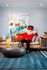 Chic living room with modern art, vibrant cushions, and an eye-catching character striking a pose on a stylish sofa.