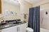 Modern bathroom with sleek dark countertop, stylish blue patterned shower curtain, and artistic wall decor.