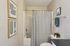 Chic bathroom with modern striped decor, featuring a sleek shower curtain and stylish wall art, perfect for contemporary living.