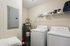 Contemporary laundry room featuring a sleek washer and dryer set, efficient water heater, and convenient shelving for storage.