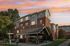 Charming apartment building with brick facade, featuring a cozy outdoor patio and lounge area under a vibrant sunset sky.