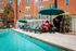 Inviting apartment complex poolside scene with sun loungers and umbrellas, offering a relaxing and vibrant outdoor space.