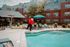 Charming apartment complex featuring a lively mascot by the refreshing pool, surrounded by a welcoming outdoor lounge area with umbrellas and sun chairs.