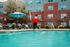 Refreshing apartment complex pool area featuring comfortable lounge chairs, vibrant blue umbrellas, and charming red brick facade.