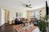 Inviting living room with contemporary decor, featuring a cozy black sofa, vibrant artwork, and large windows with natural light.