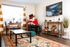 Charming living room with stylish decor, featuring a cozy armchair, vibrant area rug, and an elegant dining nook by the window.