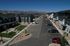 Aerial view of a modern residential community with landscaped gardens and parked cars, set against a backdrop of majestic mountains.
