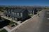 Aerial view of a sleek, contemporary apartment complex with multiple units and ample parking space set against a scenic backdrop.