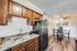 Warm kitchen with wood cabinets, black fridge, and a cozy dining area with decorative art.