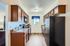 Bright kitchen with wooden cabinets, modern appliances, and a view through a blue-curtained window.