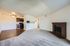 Inviting open-plan living room with warm carpet, dark wood kitchen floor, and a classic brick fireplace.