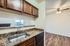 Modern kitchen with granite countertops and open view to the living area, featuring rich wooden cabinets and a sleek stainless steel faucet.