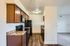 Modern kitchen with sleek countertops, wooden cabinets, and black appliances.