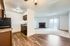 Open concept apartment with wooden floors, cozy kitchen, and a spacious living area featuring a fireplace and large window.