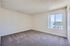Well-lit empty room with fresh carpet, large window, and textured ceiling.